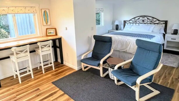 Un dormitorio con cama, dos sillas, un escritorio y una ventana.