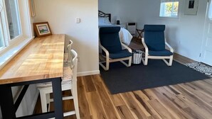 Una habitación con una mesa de comedor de madera, dos sillones azules, una mesita redonda y un tapete negro.