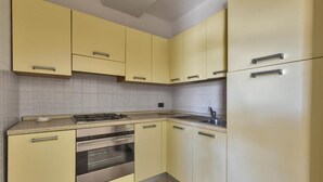 Una cocina con gabinetes amarillos, un horno de acero inoxidable, un fregadero y un refrigerador.