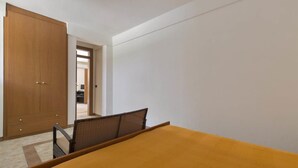 Un dormitorio con una cama, una silla y un armario.