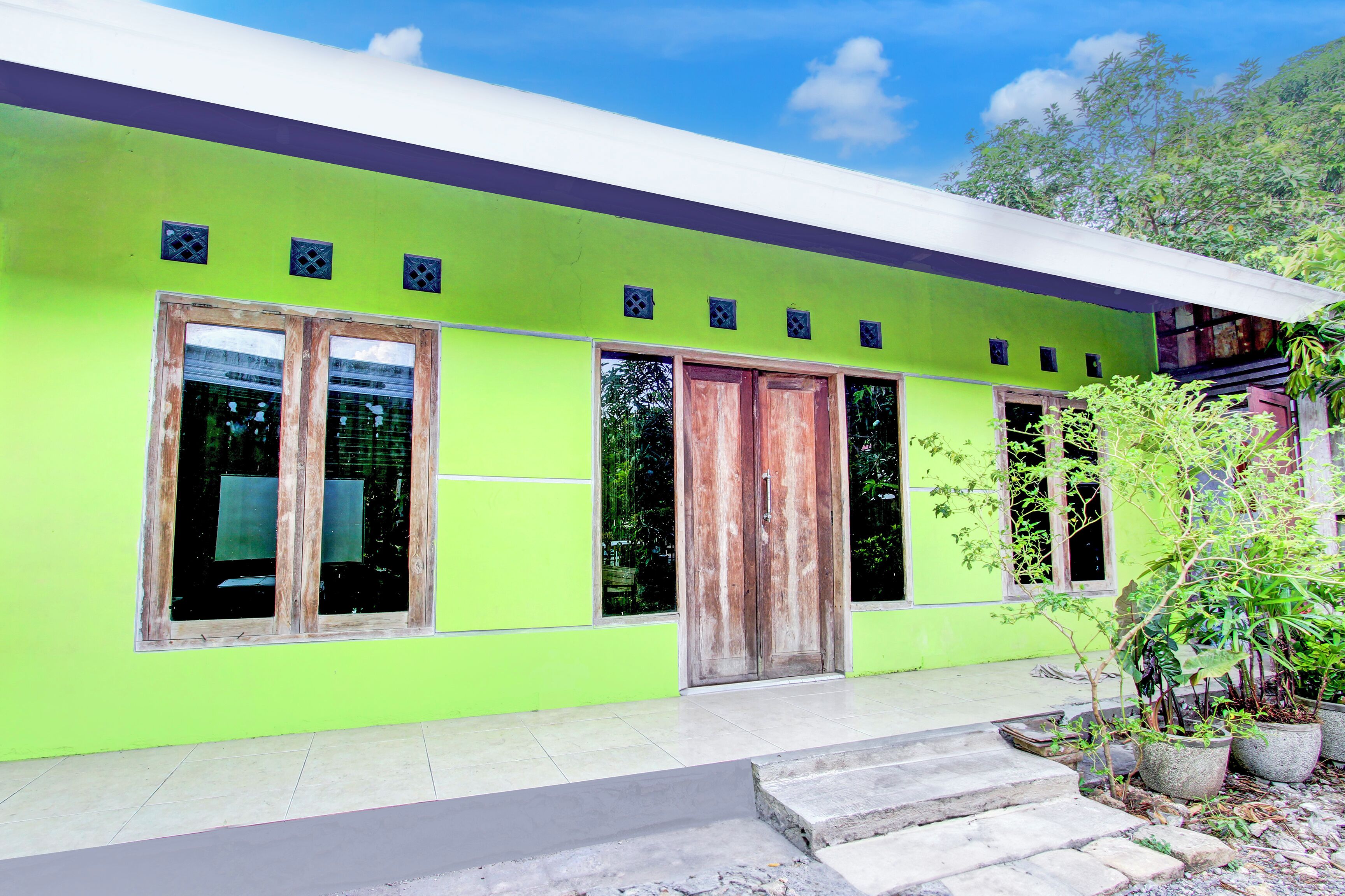 A modern building with a bright green facade, large windows, and a wooden door.
