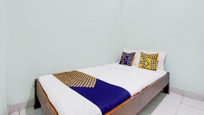A single bed with a wooden frame, white bedding, and a blue and yellow patterned bedspread. - Hotel O Juan Kostel 3 (Purwokerto)