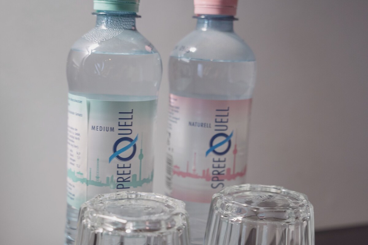 Two water bottles and two empty glasses on a table.