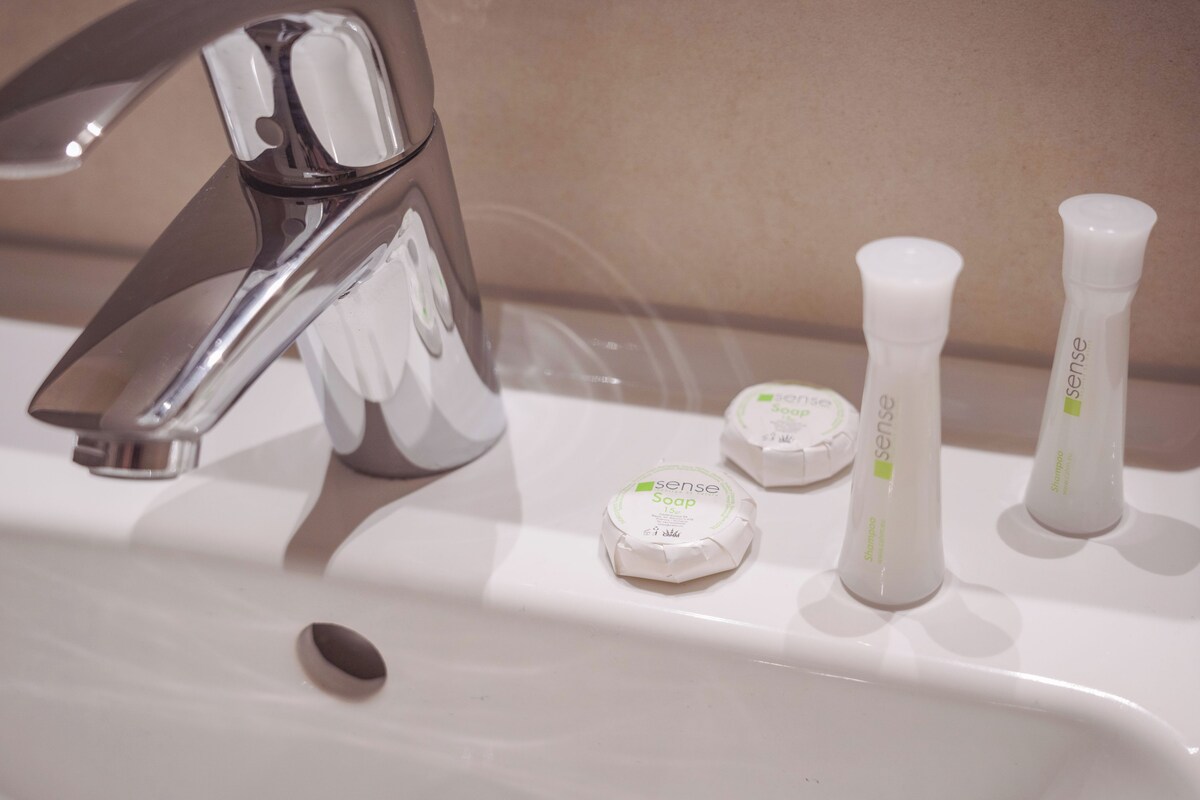 A bathroom sink with a chrome faucet, three bottles of soap, and a soap dispenser.