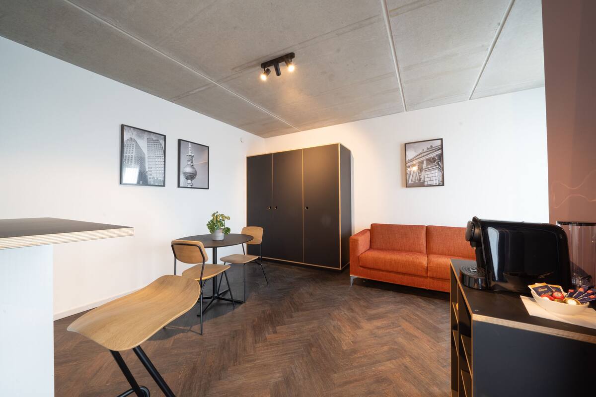 A modern room with a dining table, chairs, a sofa, and a coffee machine.