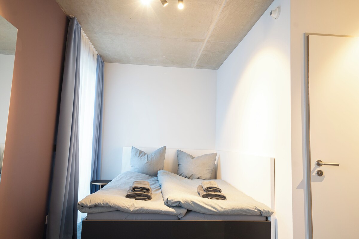 A bedroom with a bed, pillows, and a door.