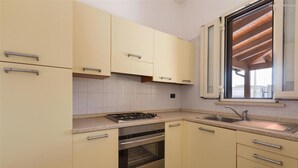 Une cuisine avec des armoires de couleur beige, un four en acier inoxydable, une cuisinière à gaz et une fenêtre ornée de poutres en bois.