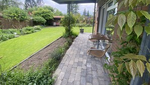 A patio with a brick pathway, a covered seating area, and a well-maintained lawn.