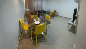 Een moderne eethoek met een glazen tafel, gele stoelen en een plafondventilator.