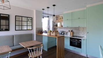 Una cocina compacta con armarios color turquesa, una isla de madera y un horno empotrado.
