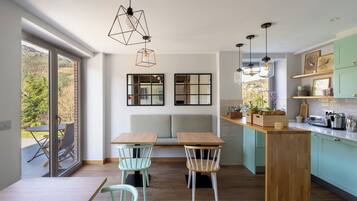 Una cocina moderna con una isla de madera, dos sillas, un banco y una mesa de comedor.