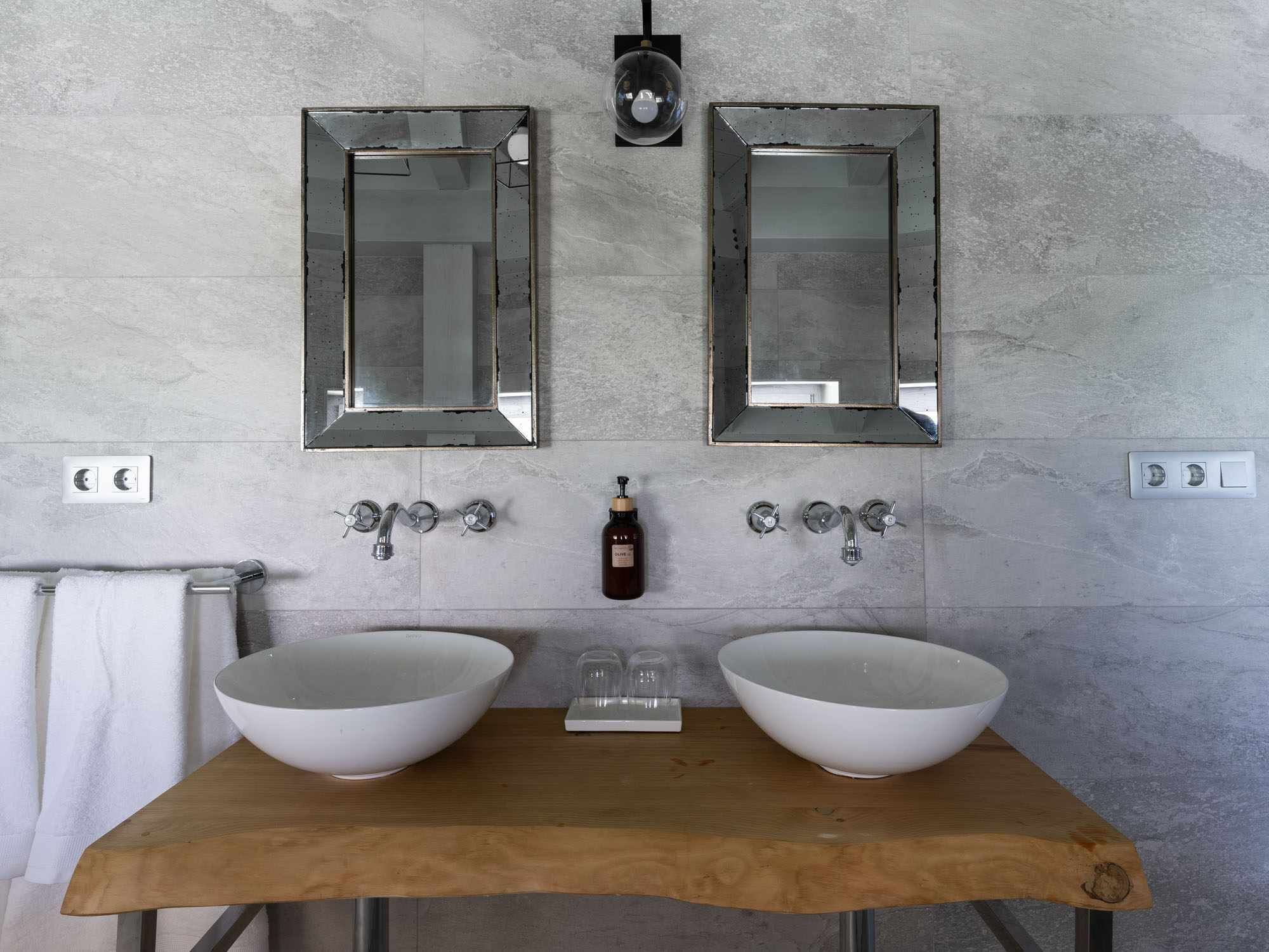 A bathroom with two large white sinks, a wooden countertop, and two wall-mounted mirrors.