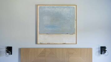 Un baño minimalista con una pared lisa, un cabecero de madera sencillo y dos luces fijadas a la pared.