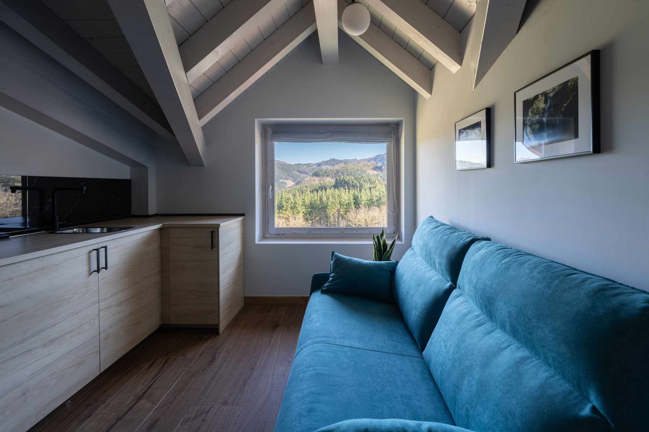 Eine moderne Küche mit Holzausstattung, einem Einbauherd und einem Fenster mit Blick auf eine Berglandschaft.