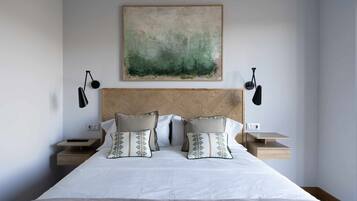 Une chambre à coucher bien aménagée, avec un grand lit, deux tables de chevet et un tableau abstrait accroché au mur.