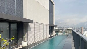 A rooftop pool with a city view, modern architecture, and a clear sky.