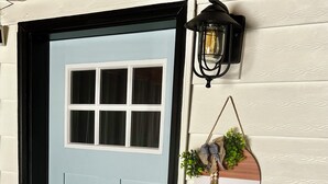 A light blue door with a black frame, a small window, and a black doorbell. - Private Entrance Guest Suite Apartment (Burns)