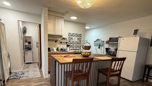A compact kitchen with a wooden island, two wooden chairs, a refrigerator, and a sink. - Private Entrance Guest Suite Apartment (Burns)