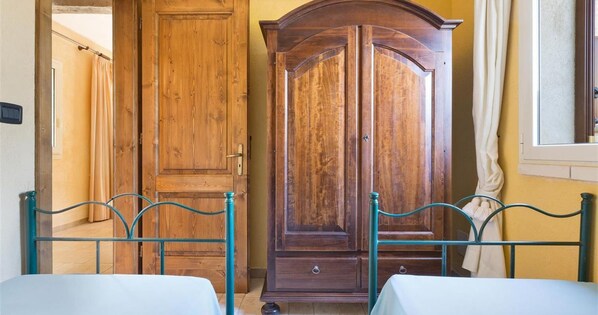 A room with two beds, a wooden wardrobe, and a window with curtains. - 835 Masseria Colosso - Camuffa (Patu)