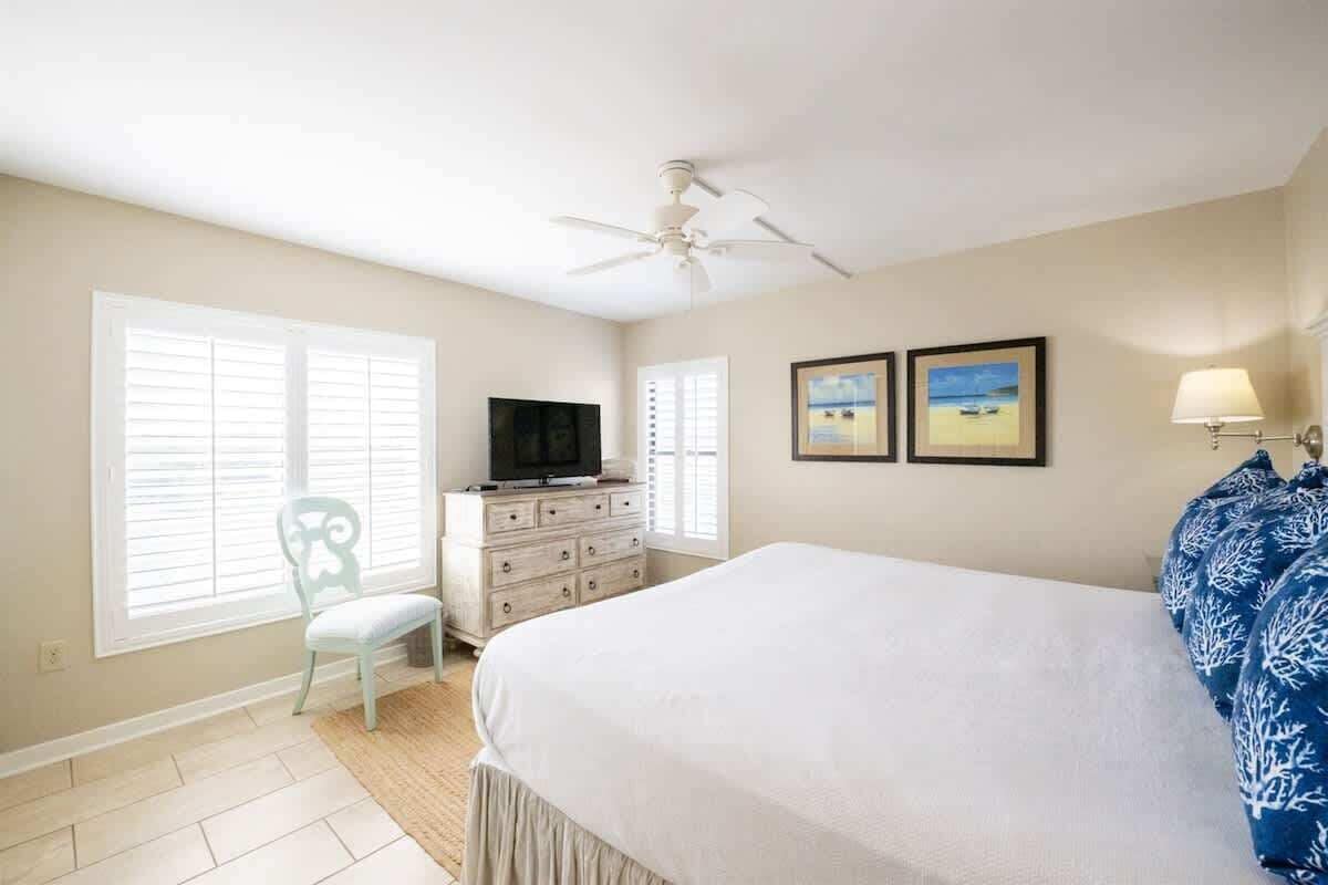 Une chambre à coucher avec un lit, une télévision, une commode et deux tableaux encadrés accrochés au mur.