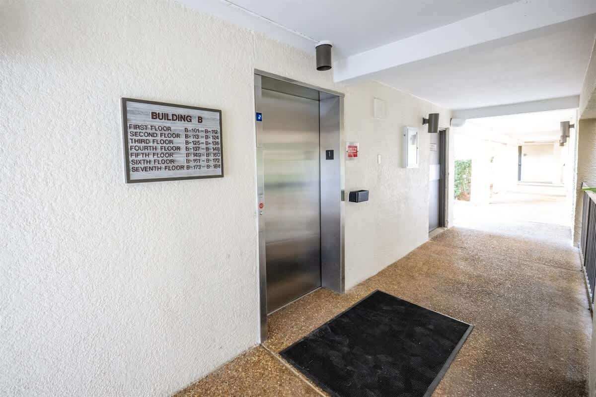 A hallway with a building sign listing floors and their corresponding room numbers.