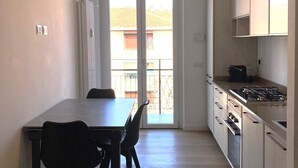 A modern kitchen with a dining area, a radiator, and a view through the glass doors. - Moderno Bilocale - Lorenteggio 145 (Milan)