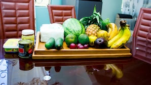 A dining table with a fruit tray, a can of food, and a bottle of sauce. - Bomang'ombe 2 room with breakfast (Boma la Ngombe)