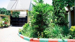 A building with a covered entrance, surrounded by lush greenery and a paved walkway. - Bomang'ombe 2 room with breakfast (Boma la Ngombe)