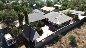 A residential area with multiple houses, some with sloped roofs and others with flat roofs. There is a paved area with a few potted plants and a small structure with a satellite dish. - Bomang'ombe 2 room with breakfast (Boma la Ngombe)