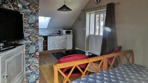 Quarto aconchegante com cama, televisão, teto de madeira e cozinha.