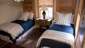 A room with two single beds, a wooden desk with a lamp, and a window with blinds. - Family Retreat for vacations, weddings, family reunions and corporate retreats.  (Florence)