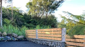 A parking area with a gravel surface, a wooden fence, and a stone wall. - LES Panoramiks DES Makes, Villas DE Charmes (Saint-Louis)