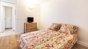 A bedroom with a bed, a dresser, a television on top, and a door leading to a bathroom. - GuestReady - calming nest near Place d'Italie (Paris)