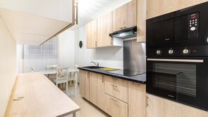 A modern kitchen with wooden cabinets, a black countertop, a stainless steel range hood, and a built-in oven. - GuestReady - calming nest near Place d'Italie (Paris)
