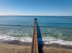 A long pier extending into the ocean with a clear sky above.