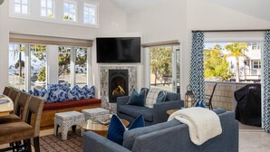 A spacious living room with a fireplace, comfortable seating, and large windows offering a view of the outdoors. - Avila with a view! sleeps 5 (Avila Beach)