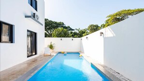 A modern pool area with a clear blue pool, white walls, and a small plant. - Ultimate ’ Retreat with Pool & Beach Vibes!” (Sosúa)