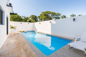A swimming pool with two white lounge chairs, surrounded by a white wall and a tiled floor. - Ultimate ’ Retreat with Pool & Beach Vibes!” (Sosúa)