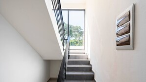 A modern staircase with a glass railing leading to a bright room with a large window. - Ultimate ’ Retreat with Pool & Beach Vibes!” (Sosúa)