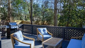 An outdoor deck with wicker furniture, a grill, and a wooden fence. - Gateway to Heaven is in Historic Roswell! (Roswell)
