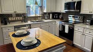 A modern kitchen with white cabinets, a stainless steel oven, a microwave, and a coffee station. - Gateway to Heaven is in Historic Roswell! (Roswell)