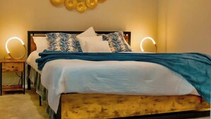 A bedroom with a bed, a ceiling fan, wall sconces, and a decorative wall piece. - Gateway to Heaven is in Historic Roswell! (Roswell)