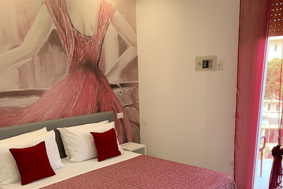 A bedroom with a large bed, a headboard, and a wall mural.