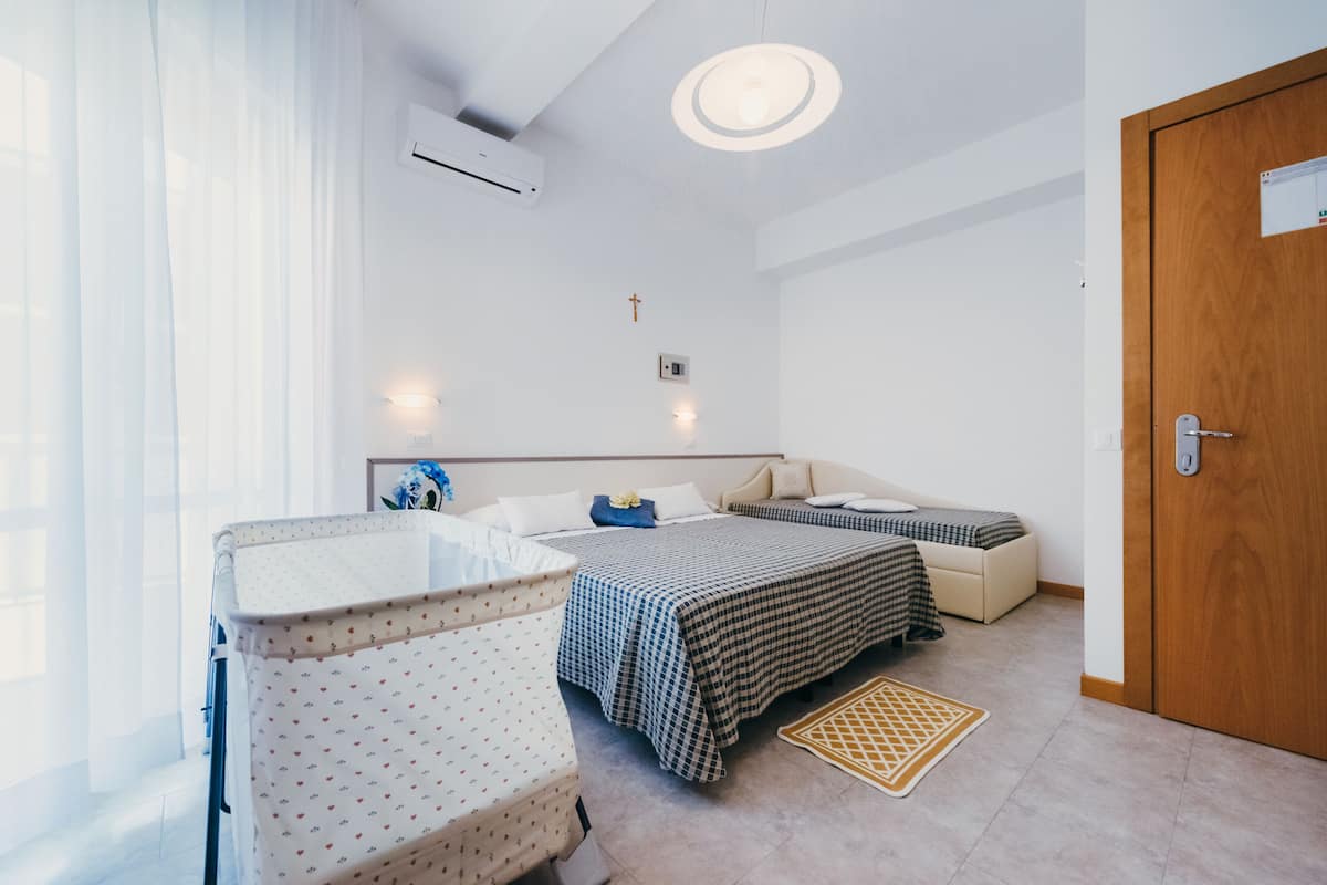 A bedroom with a bed, a sofa, a baby changing station, and a wooden door.