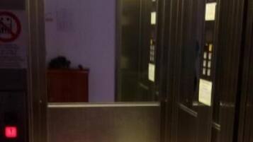 Un ascensor vacío con paredes metálicas y un panel de control a la izquierda.
