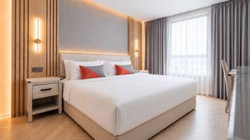 A modern hotel room with a large bed, bedside tables, and a view of the city through the window.