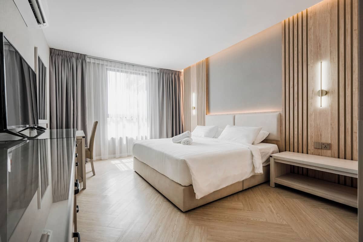 A modern hotel room with a large bed, bedside table, and a TV.