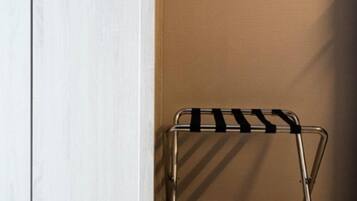Una habitación con un armario blanco, un tendedero metálico y suelo de madera.