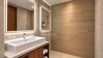 A modern bathroom with a large mirror, a sink, and a shower.