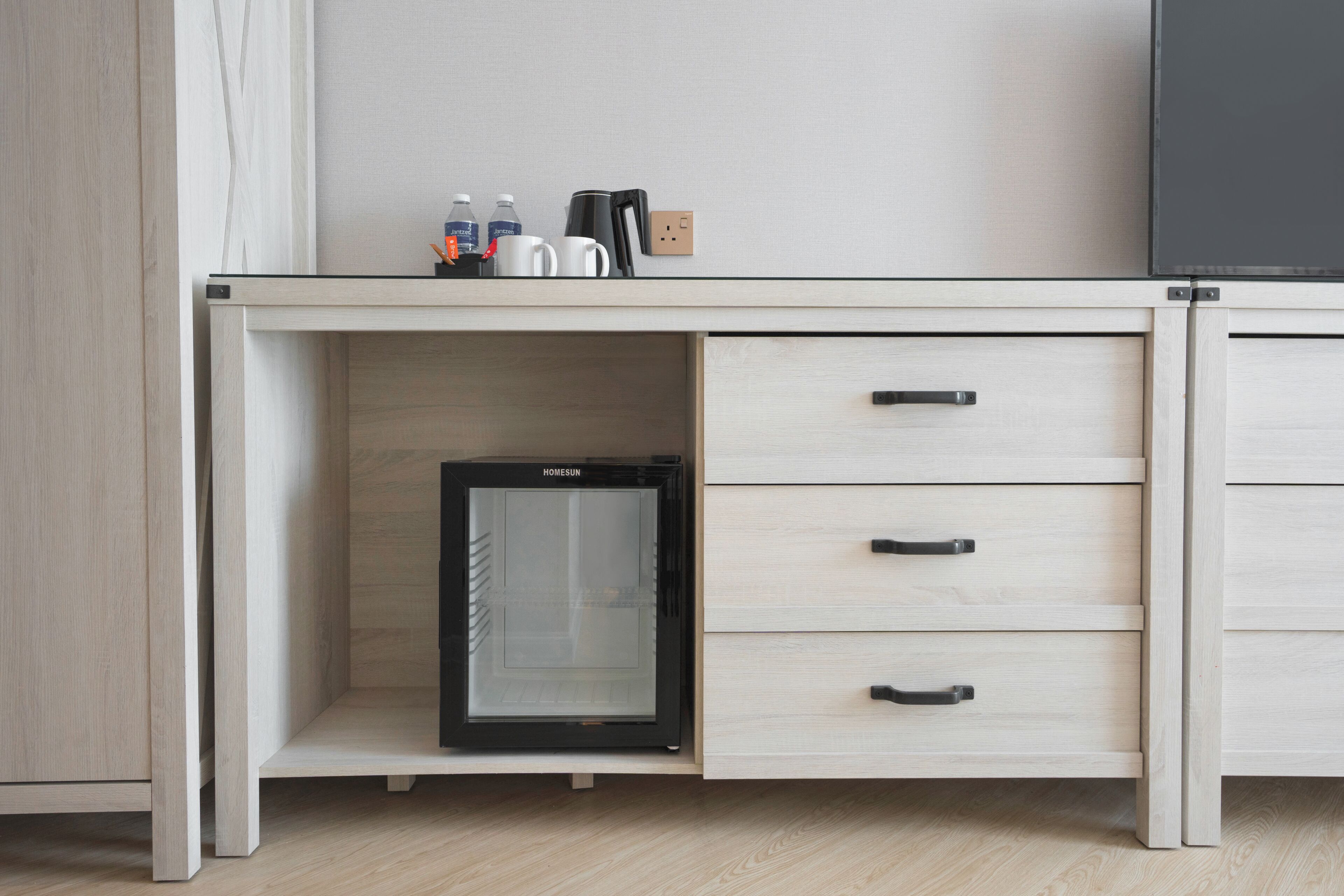 A modern kitchen with a built-in mini-fridge, a coffee maker, and a kettle on the countertop.